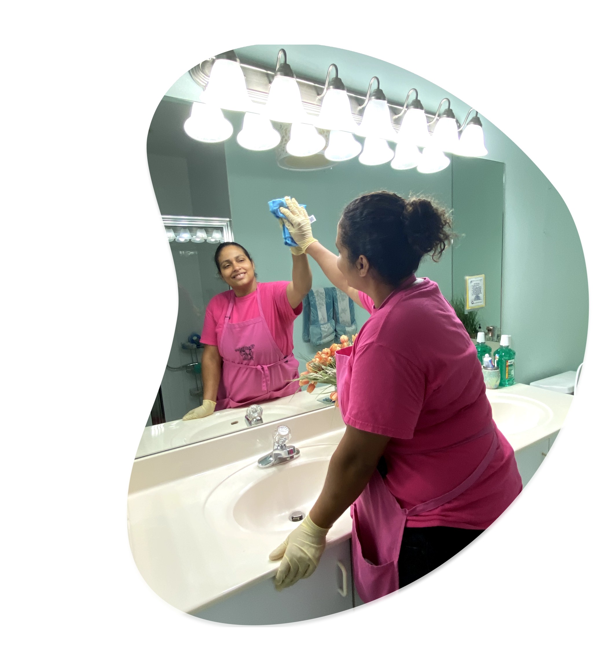 happy executive maid professional house cleaner wiping glass mirror in bathroom